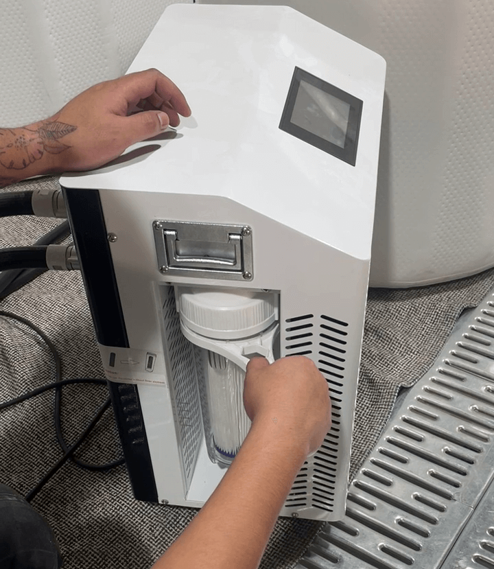 Person performing ice bath maintenance by accessing the cleaning filter on a professional unit.