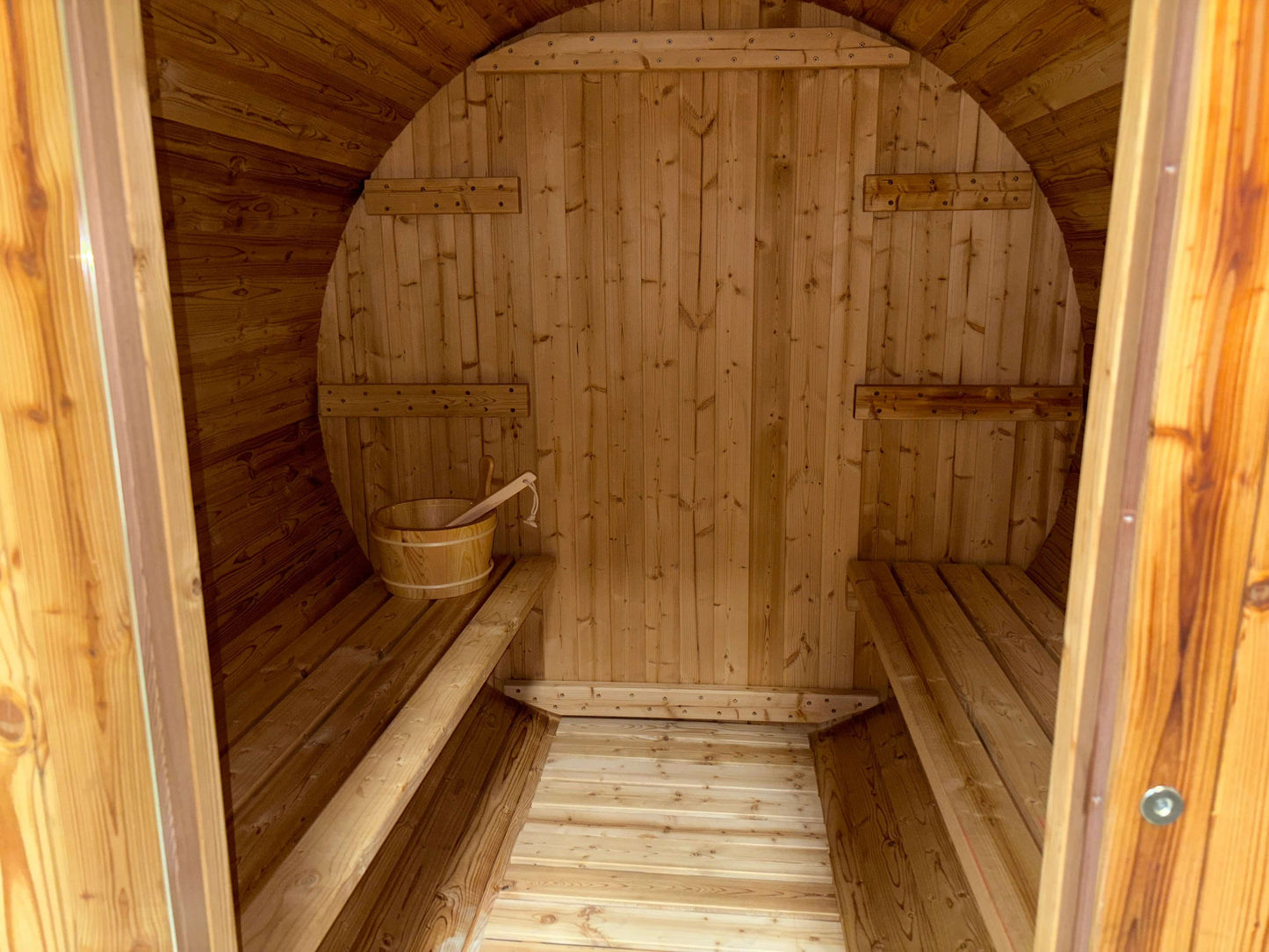 Interior view of a ThermoElite sauna featuring warm wood finishes, benches, and a wooden bucket.