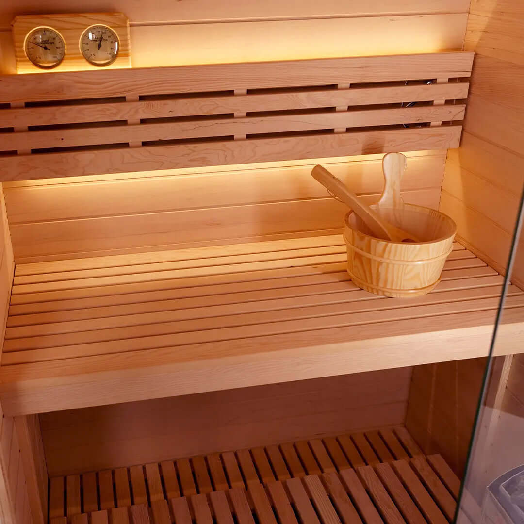 Interior view of sauna with wooden slatted benches, a wooden bowl, and temperature gauges, showcasing a premium sauna experience.